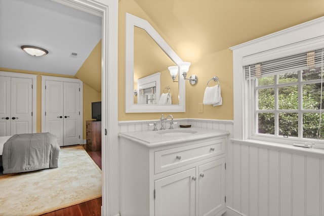 bathroom featuring visible vents, ensuite bathroom, wainscoting, vaulted ceiling, and vanity