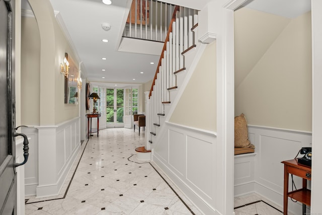 entrance foyer featuring recessed lighting, wainscoting, a decorative wall, and stairs