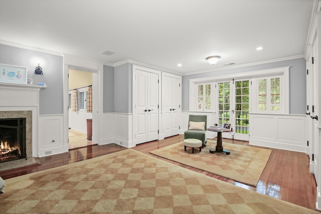114 Ferris Hill Rd, New Canaan, CT 06840 - sitting room featuring crown molding, wood-type flooring, a high end fireplace, a decorative wall, and wainscoting