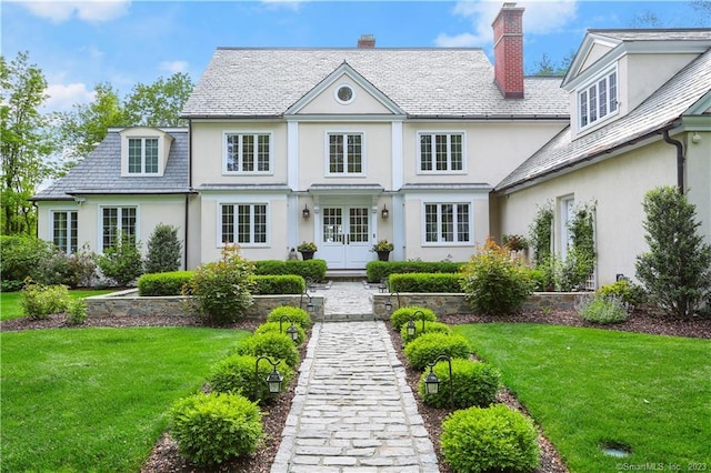 back of property with a lawn and french doors