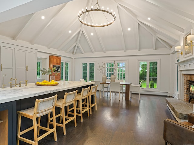 kitchen with a breakfast bar area, vaulted ceiling with beams, light stone countertops, and a chandelier