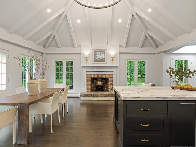 kitchen with beamed ceiling, light stone counters, plenty of natural light, and dark wood-type flooring