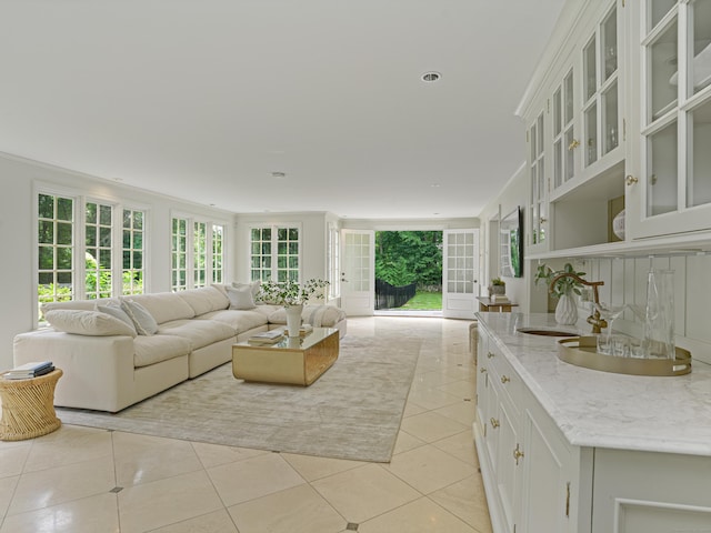 living room with crown molding, sink, and light tile patterned floors