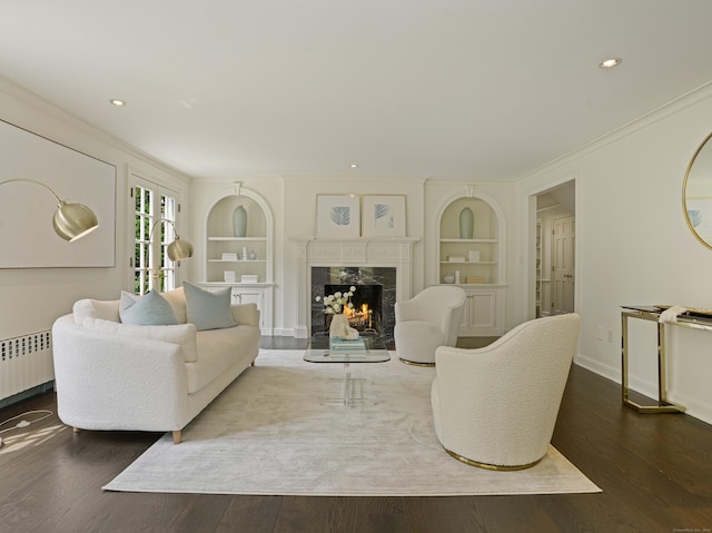 living room with dark hardwood / wood-style flooring, a premium fireplace, built in features, and radiator heating unit