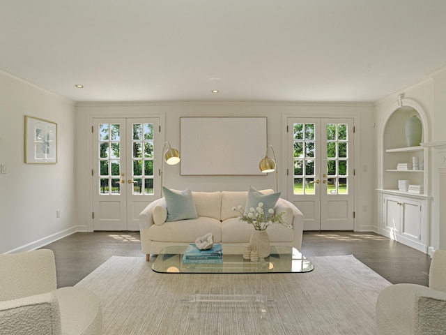 unfurnished living room featuring plenty of natural light, built in features, ornamental molding, and french doors