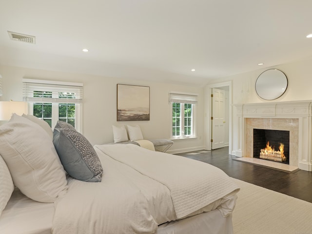 bedroom with dark hardwood / wood-style flooring and a fireplace