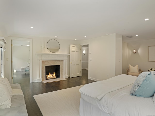 bedroom with dark hardwood / wood-style flooring and a premium fireplace