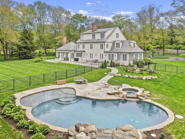 rear view of house featuring a lawn, a patio, and a pool with hot tub