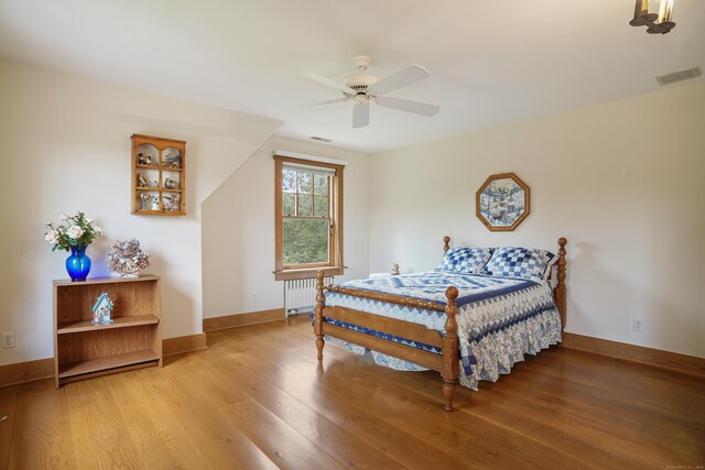 bedroom featuring ceiling fan, radiator, and hardwood / wood-style flooring