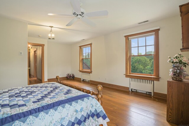 bedroom with radiator, hardwood / wood-style floors, and multiple windows