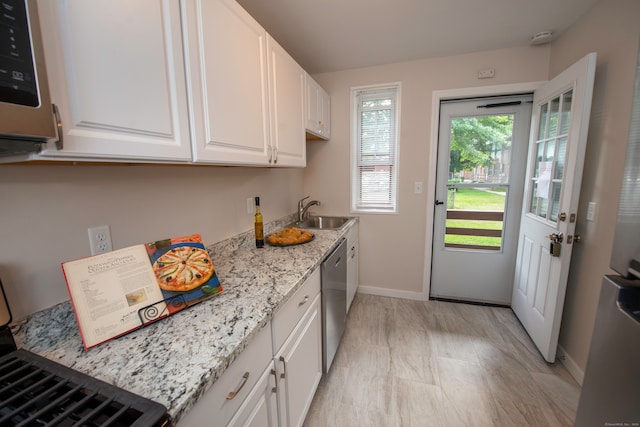 kitchen featuring white cabinets, light stone counters, dishwasher, and sink