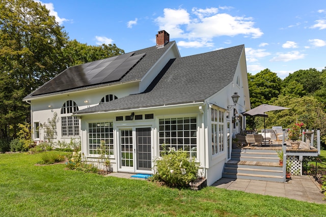 rear view of house with solar panels, a yard, and a deck