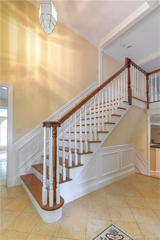 12 W Mountain Rd, Sharon, CT 06069 - stairs featuring tile patterned flooring, a high ceiling, a decorative wall, and crown molding