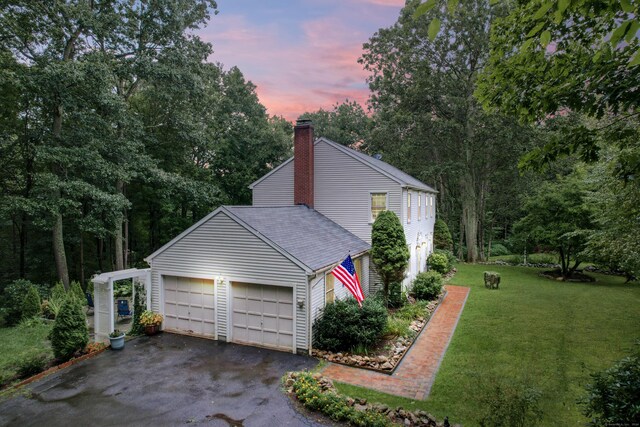 property exterior at dusk featuring a lawn and a garage