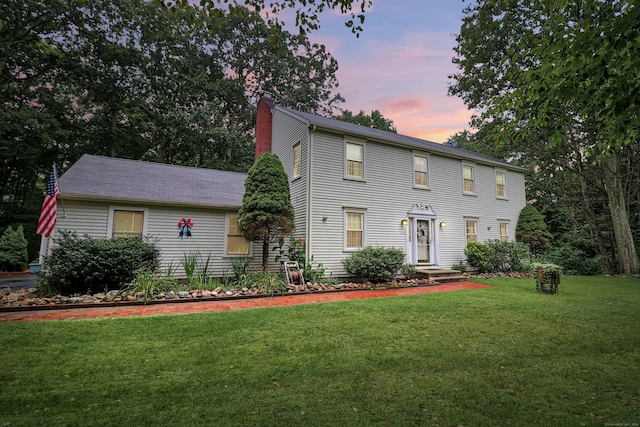 colonial-style house with a chimney and a front yard