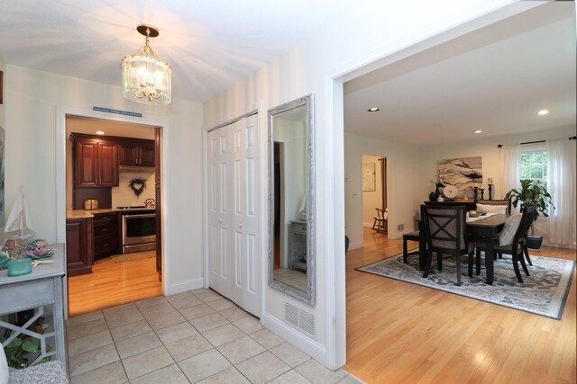 hall featuring light tile patterned floors and an inviting chandelier