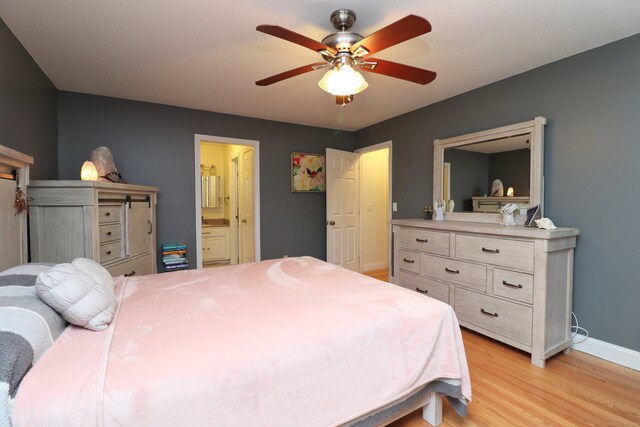 bedroom featuring ceiling fan, light hardwood / wood-style floors, and ensuite bath