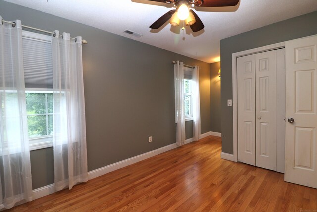 unfurnished bedroom featuring ceiling fan, a closet, and wood-type flooring