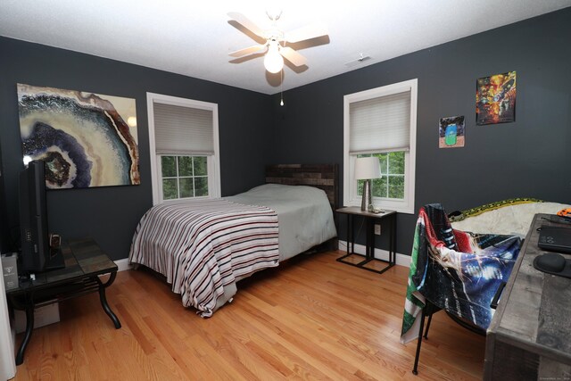 bedroom featuring multiple windows, light wood-type flooring, and ceiling fan