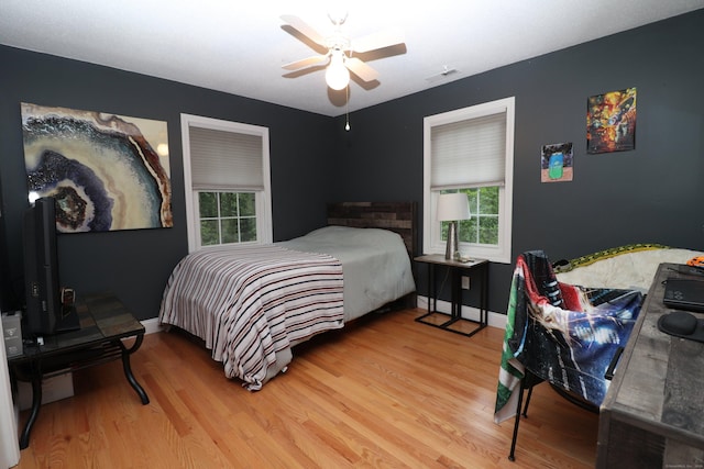 bedroom with ceiling fan, wood finished floors, visible vents, and baseboards