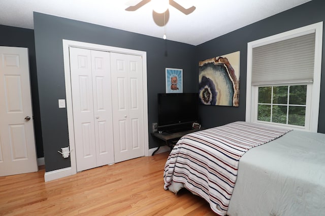 bedroom featuring baseboards, light wood-style flooring, a ceiling fan, and a closet