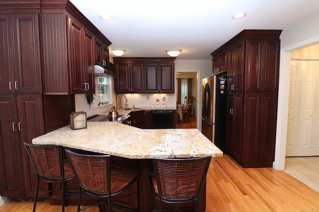 kitchen with a peninsula, a breakfast bar, a sink, and freestanding refrigerator