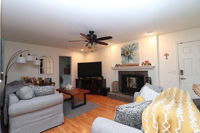 living room featuring light hardwood / wood-style flooring, ceiling fan, and a tile fireplace