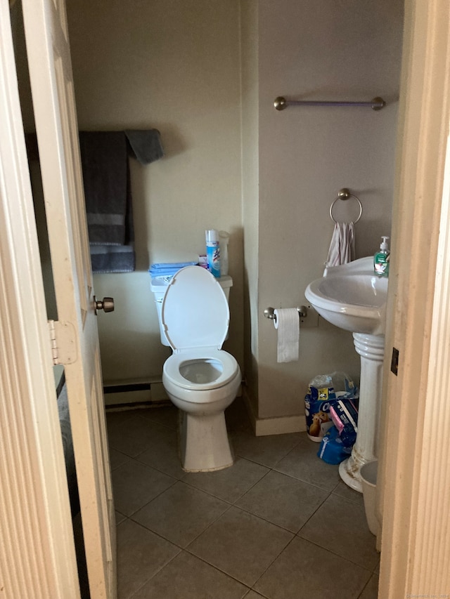 bathroom with a baseboard heating unit, toilet, and tile patterned flooring