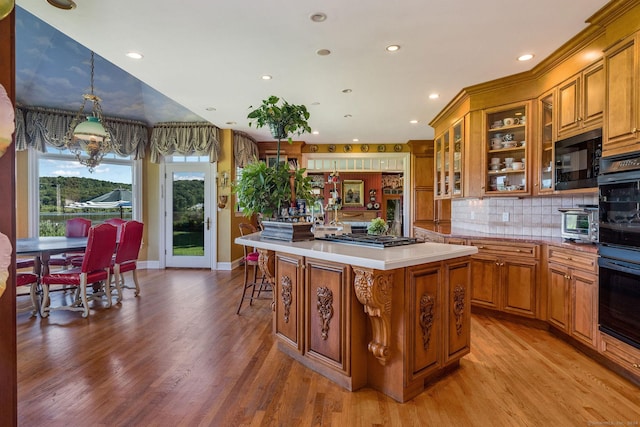 kitchen with a kitchen island, decorative backsplash, light hardwood / wood-style floors, hanging light fixtures, and stainless steel gas stovetop