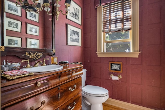 bathroom with toilet, vanity, and an inviting chandelier