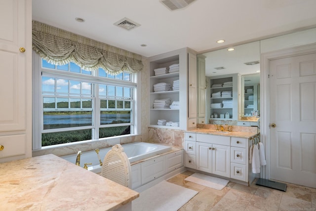 bathroom featuring a water view, a tub, built in features, and vanity