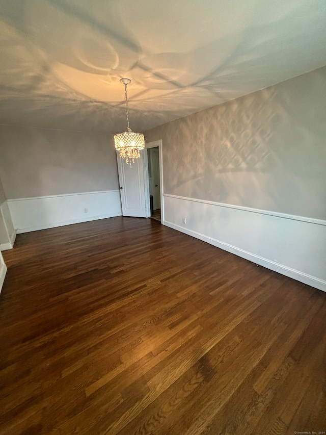 unfurnished dining area with dark wood-type flooring and a notable chandelier