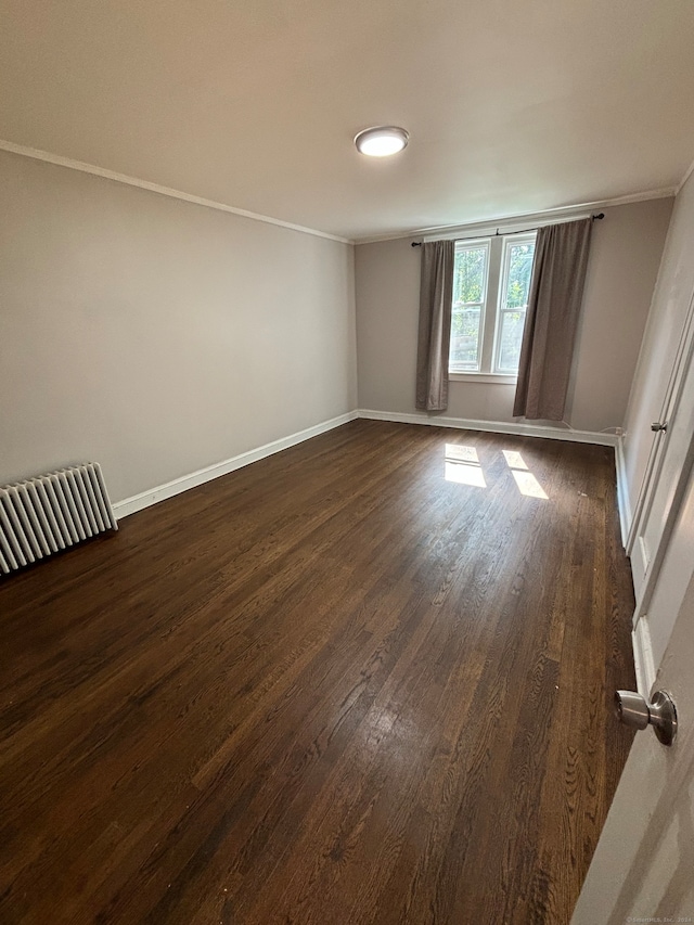 spare room featuring dark wood-type flooring and ornamental molding