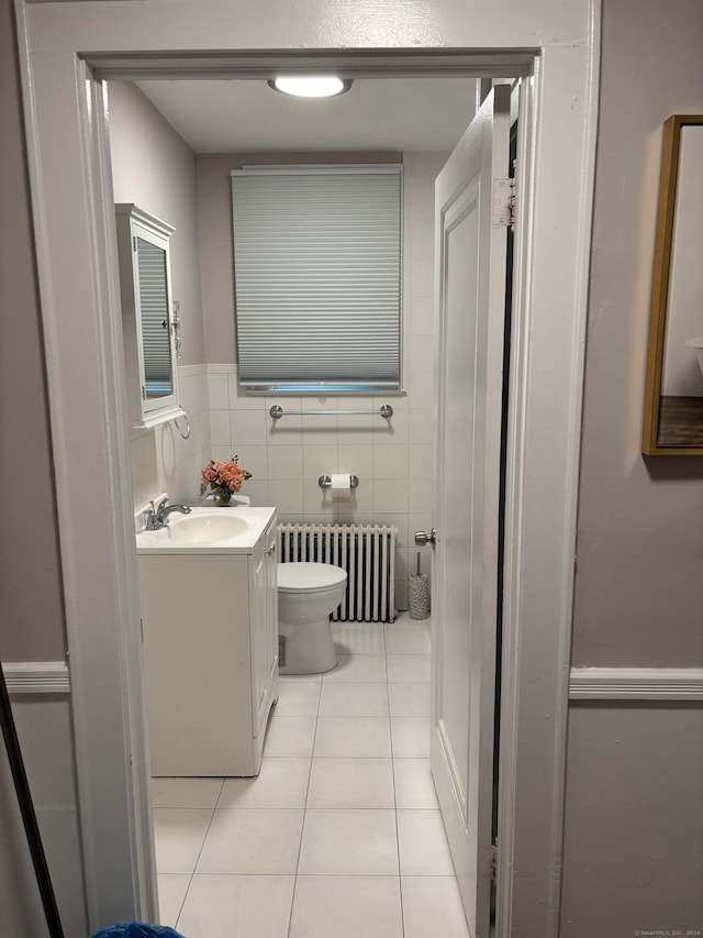 bathroom featuring radiator heating unit, toilet, vanity, tile walls, and tile patterned floors