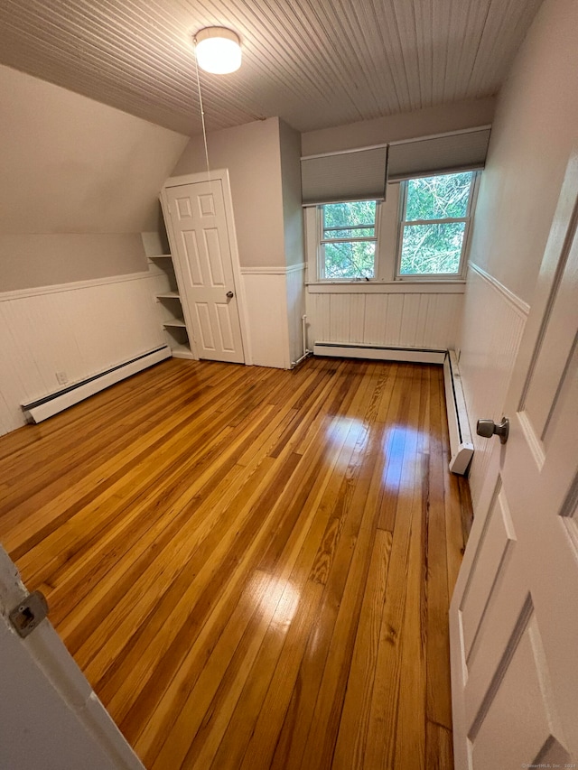 additional living space with light hardwood / wood-style floors, baseboard heating, and lofted ceiling