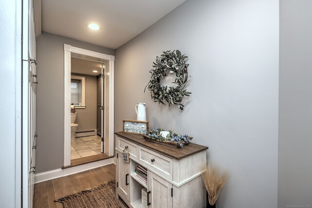 corridor featuring baseboard heating and dark hardwood / wood-style floors