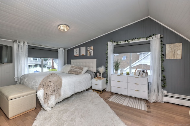 bedroom with a baseboard heating unit, lofted ceiling, light hardwood / wood-style floors, and crown molding