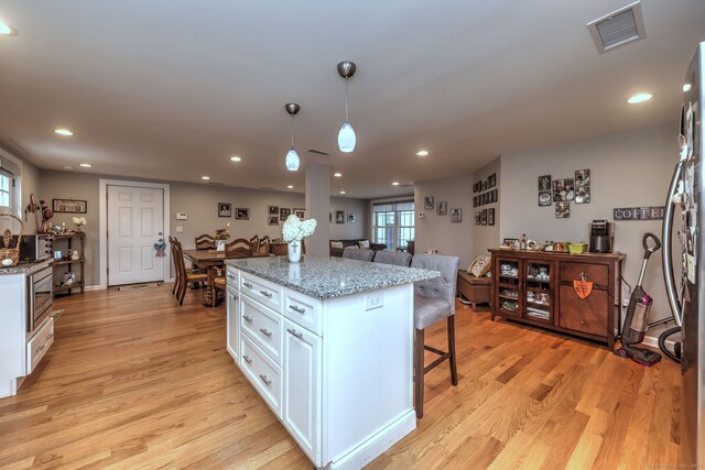 kitchen featuring white cabinets, plenty of natural light, light wood-type flooring, and decorative light fixtures