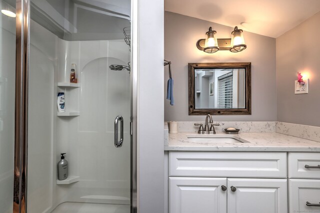 bathroom with lofted ceiling, walk in shower, and vanity