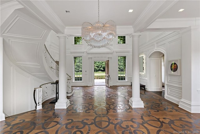 foyer entrance with ornate columns, crown molding, and a notable chandelier