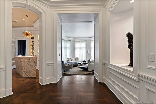 hall with ornamental molding, a chandelier, and dark parquet floors