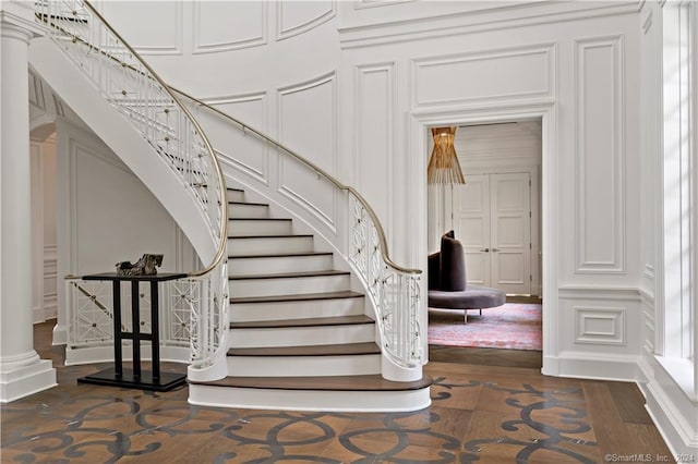 stairway with hardwood / wood-style flooring and decorative columns