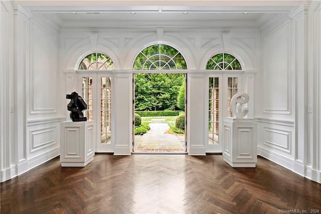 doorway featuring crown molding and dark parquet flooring