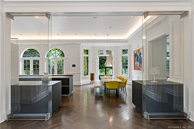 interior space featuring ornamental molding, dark parquet flooring, a kitchen island, and white cabinets