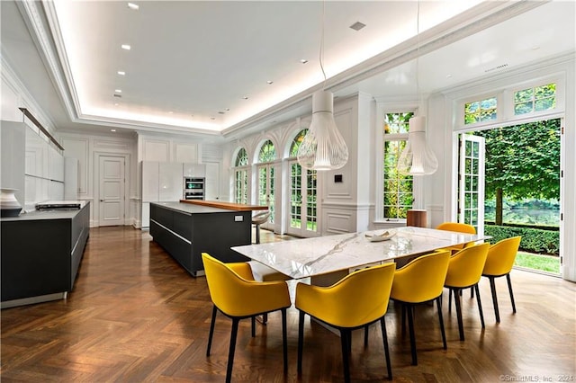 dining area with a tray ceiling, ornamental molding, a wealth of natural light, and dark parquet flooring