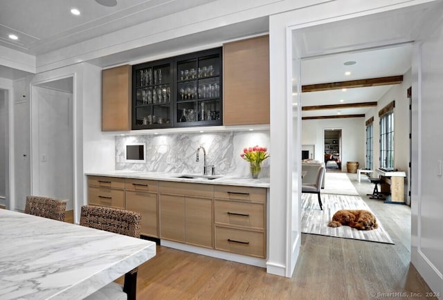 bar with beamed ceiling, light hardwood / wood-style flooring, a fireplace, and sink