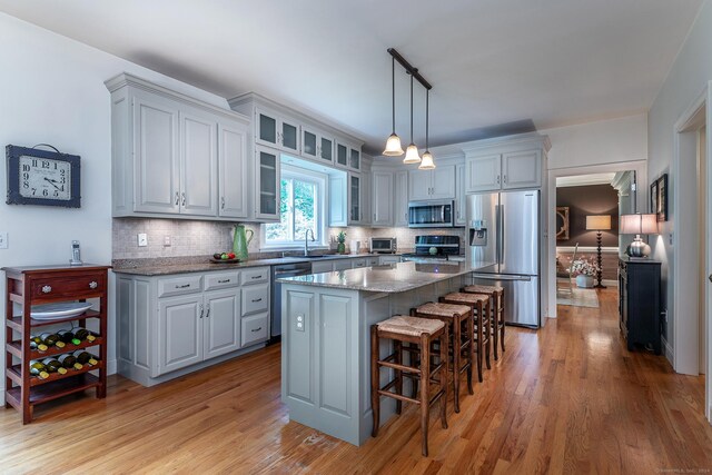 kitchen featuring a sink, a kitchen breakfast bar, appliances with stainless steel finishes, a center island, and tasteful backsplash