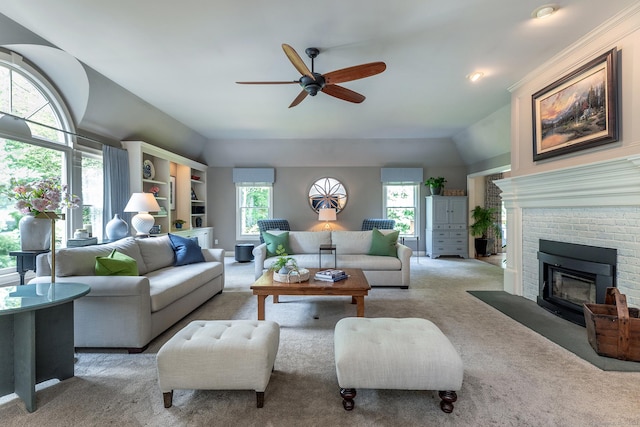 living area featuring lofted ceiling, carpet floors, a brick fireplace, and a ceiling fan