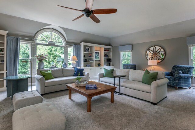 living room with lofted ceiling, ceiling fan, and carpet