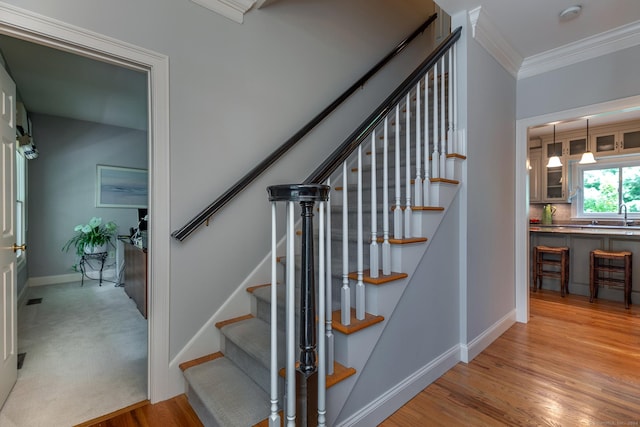 stairway featuring ornamental molding, baseboards, and wood finished floors